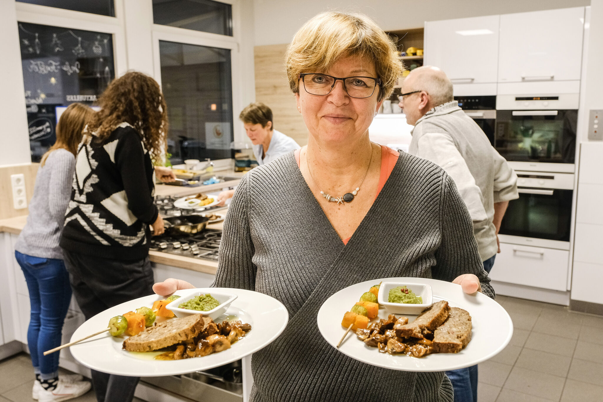 Bettina Nebe mit dem Hauptgang: Nussbraten, marinierte Mischpilze und Rosenkohl-Kürbis-Spieße mit Pesto. Ein Weihnachtsessen ganz ohne Fleisch – das ist der Plan bei einem Kochkurs in der Familien-Bildungsstätte. Foto: epd-bild/Jens Schulze