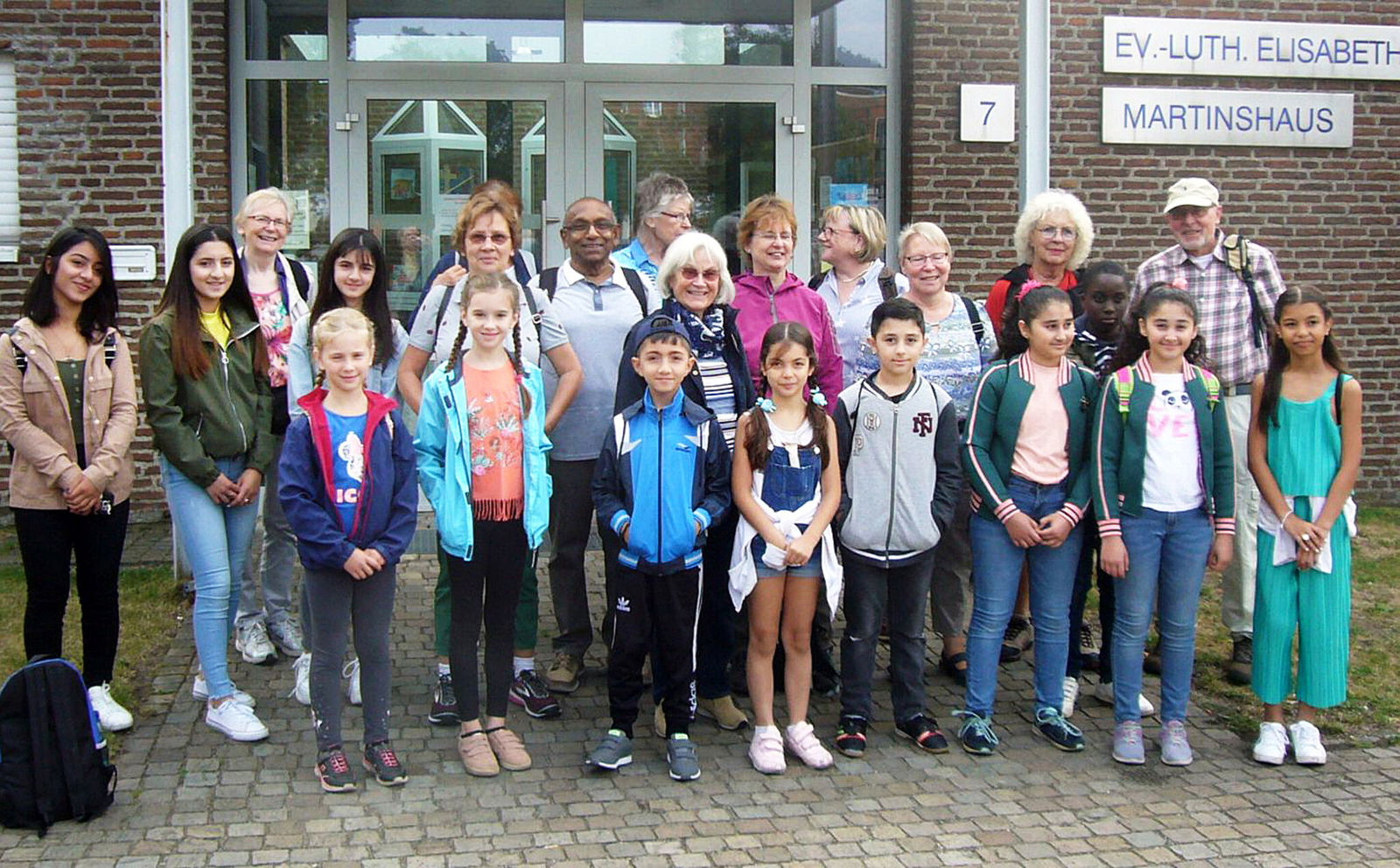 Inge Collatz (Mitte, mit Halstuch), ehrenamtlich Mitarbeitende der Lernhilfe und die Kinder und Jugendlichen im Jahr 2020 vor dem Gemeindehaus der Elisabethkirche. Foto: Archiv