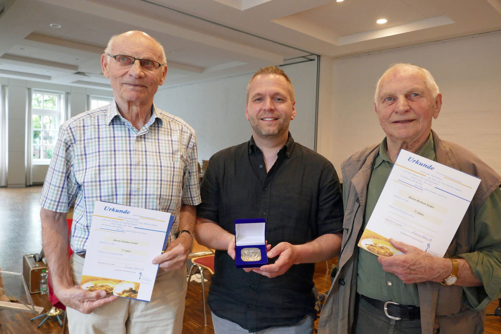 Landesposaunenwart Henning Herzog (Mitte) überreicht Urkunden und Kuhlo-Medaillen an Günther Seidel (links) und Herbert Seidel für die 75-jährige aktive Mitgliedschaft in Posaunenchören. Foto: Sabine Freitag
