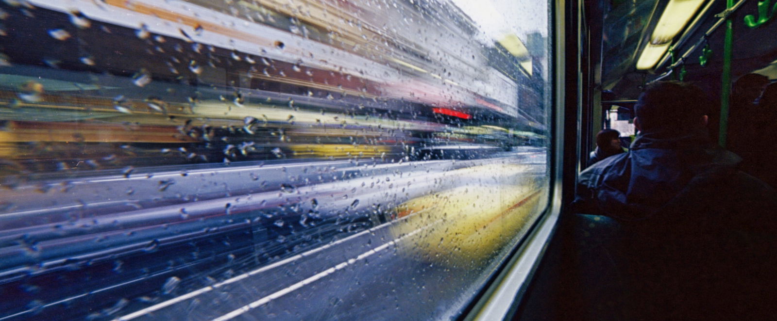 Blick aus einem Bahnabteil. Die Umgebung rauscht am Fenster vorbei.