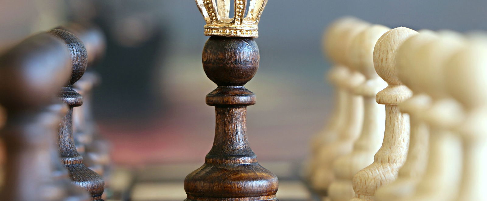 Ein Schachbrett mit Bauern. In der Mitte steht ein Bauer mit Königskrone.