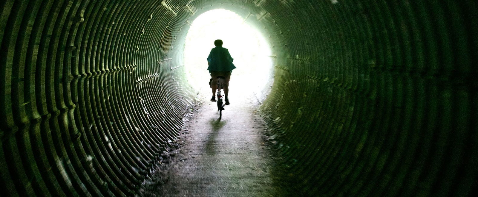 Ein Fahrradfahrer fährt auf das Licht am Ende eines Tunnels zu.