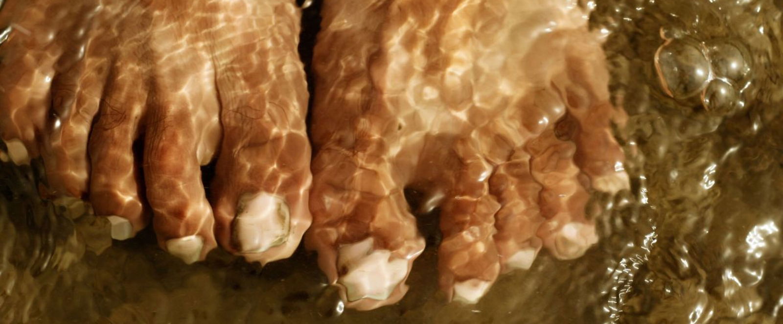 Ein paar Füße in flachem, klaren Wasser