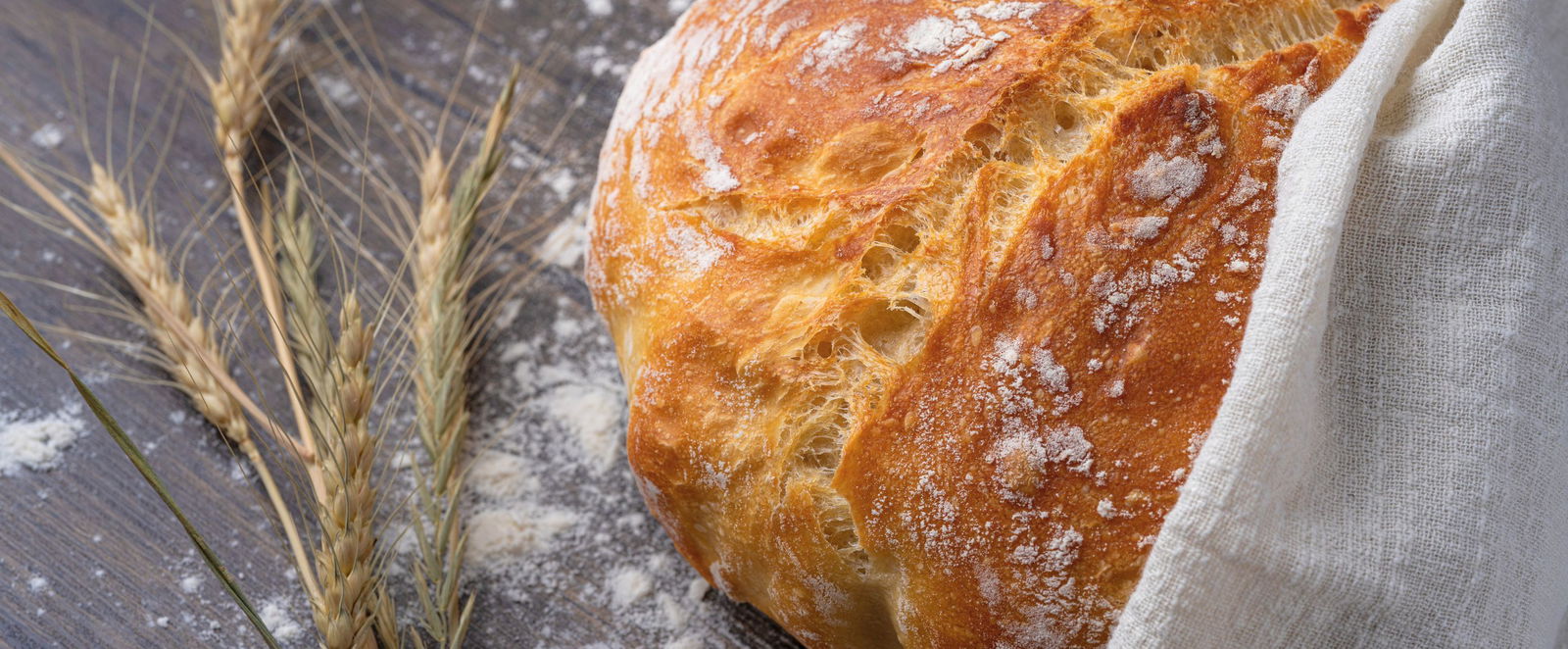 ein Brotlaib und Weizenkoerner auf einer Tischplatte
