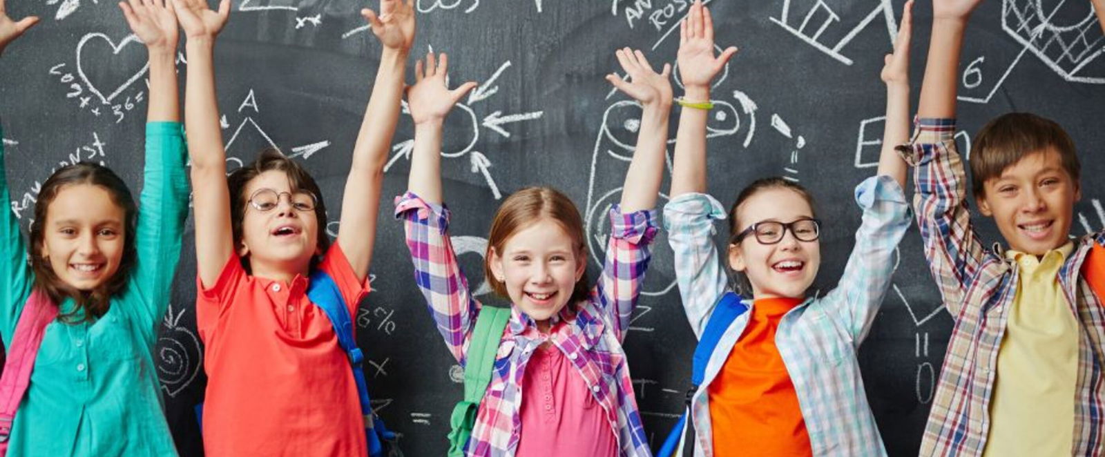 Fünf Kinder stehen vor einer Tafel mit komplizierten Symbolen und recken die Arme in die Höhe.