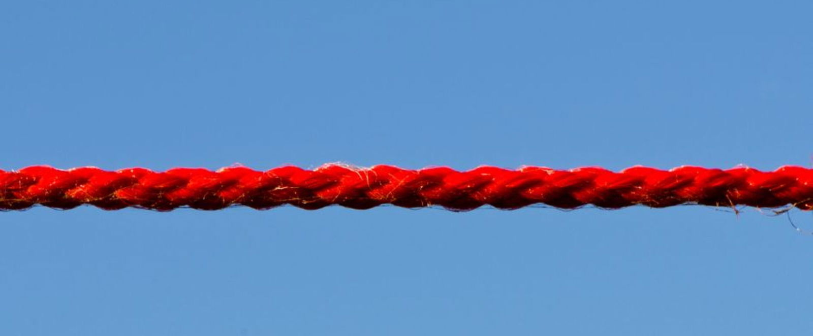 Ein rotes Seil vor blauem Himmel.