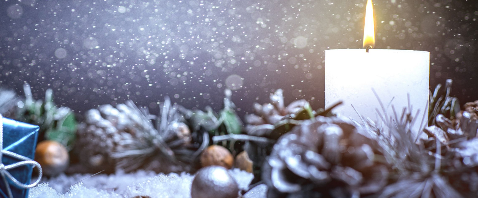 Eine weiße Kerze brennt in einem Adventsgeschenk.