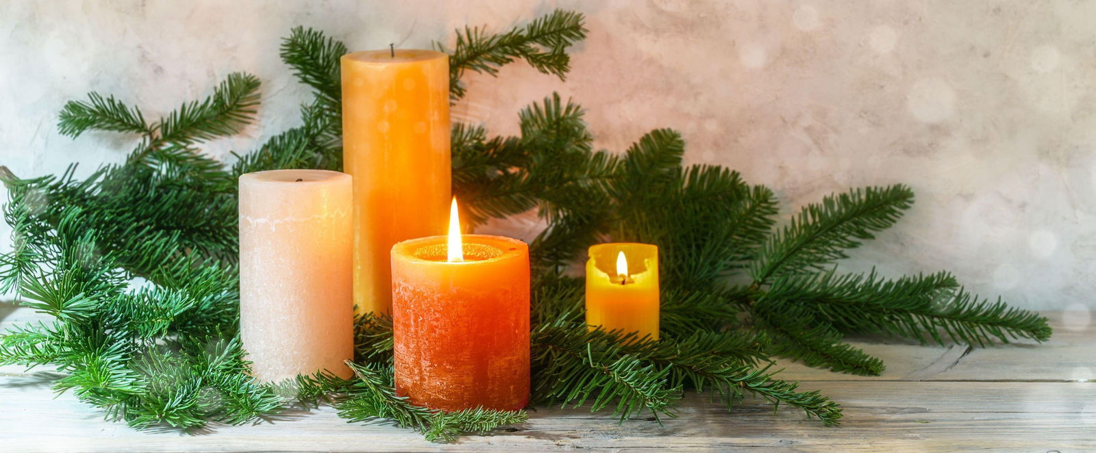 Ein Adventskranz mir vier orangefarbenen Kerzen, zwei davon brennen.