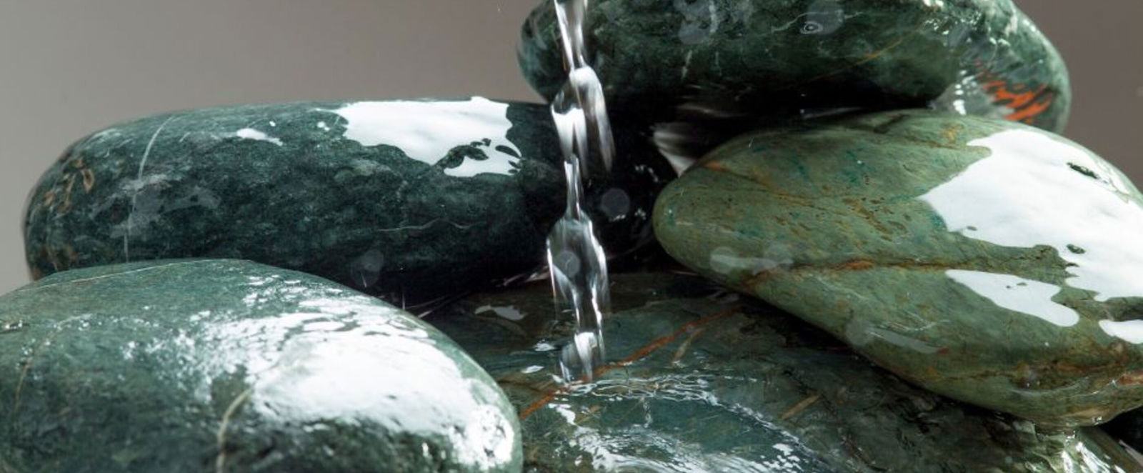 Ein Wasserstrahl läuft auf einen Haufen Steine hinunter.