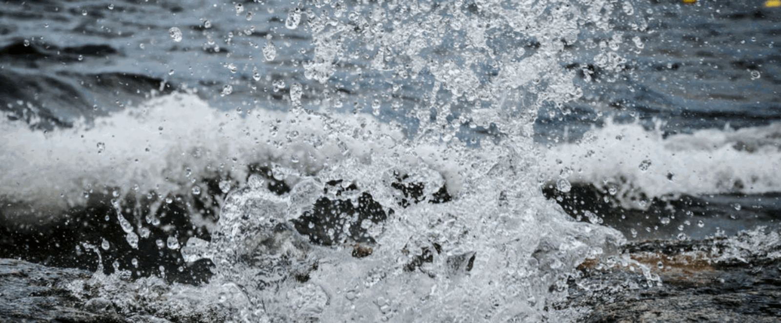 Wasser eines Flusses spritzt auf, als es auf Steine prallt.