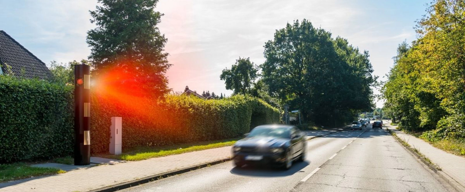 Ein zu schnell fahrendes Auto wird geblitzt.