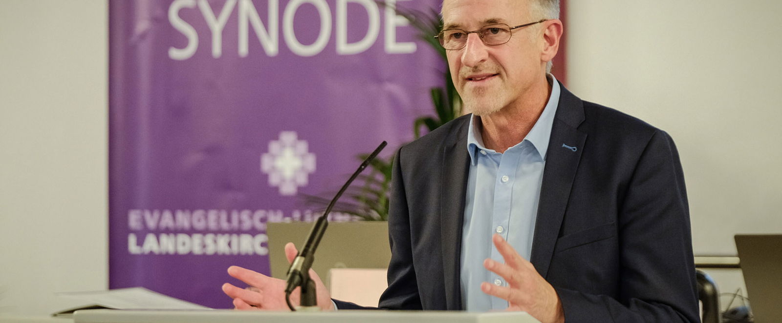 Eine männlich gelesene Person am Redepult. 