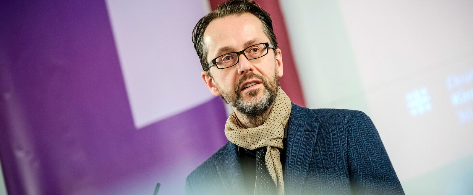 Eine männlich lesbare Person an einem Rednerpult