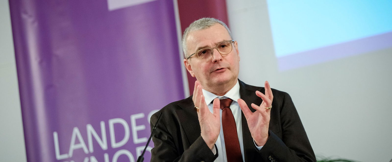 Eine männlich lesbare Person an einem Rednerpult