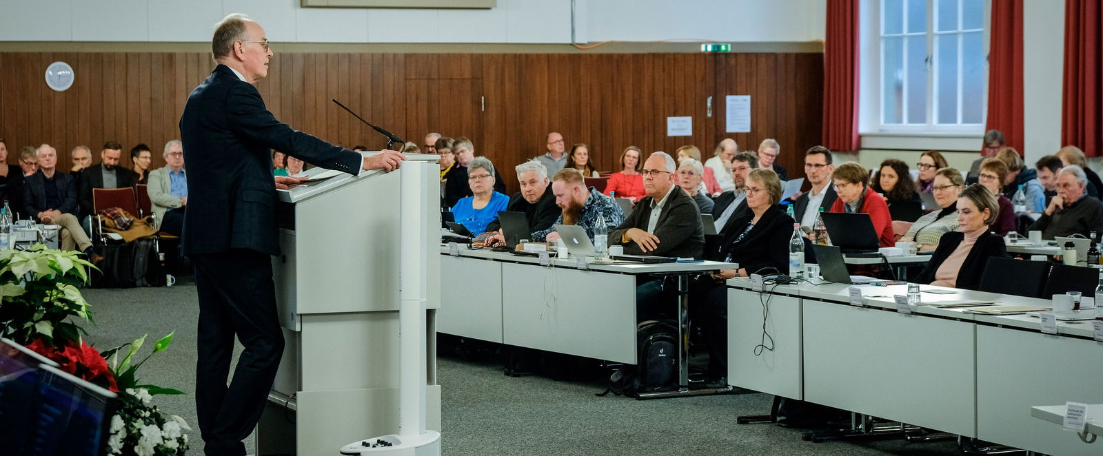 Eine männlich lesbare Person im Anzug steht am Podium