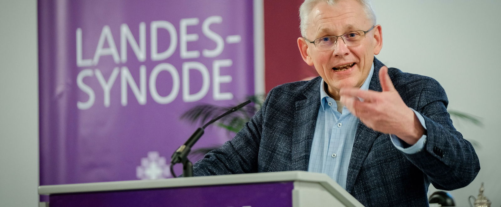 Eine männlich lesbare Person steht am Rednerpult und spricht.