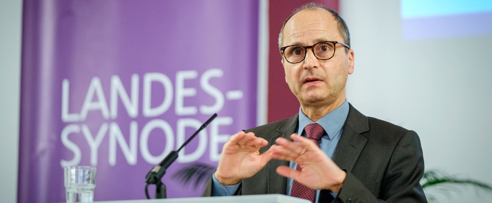 Eine männlich lesbare Person an einem Rednerpult