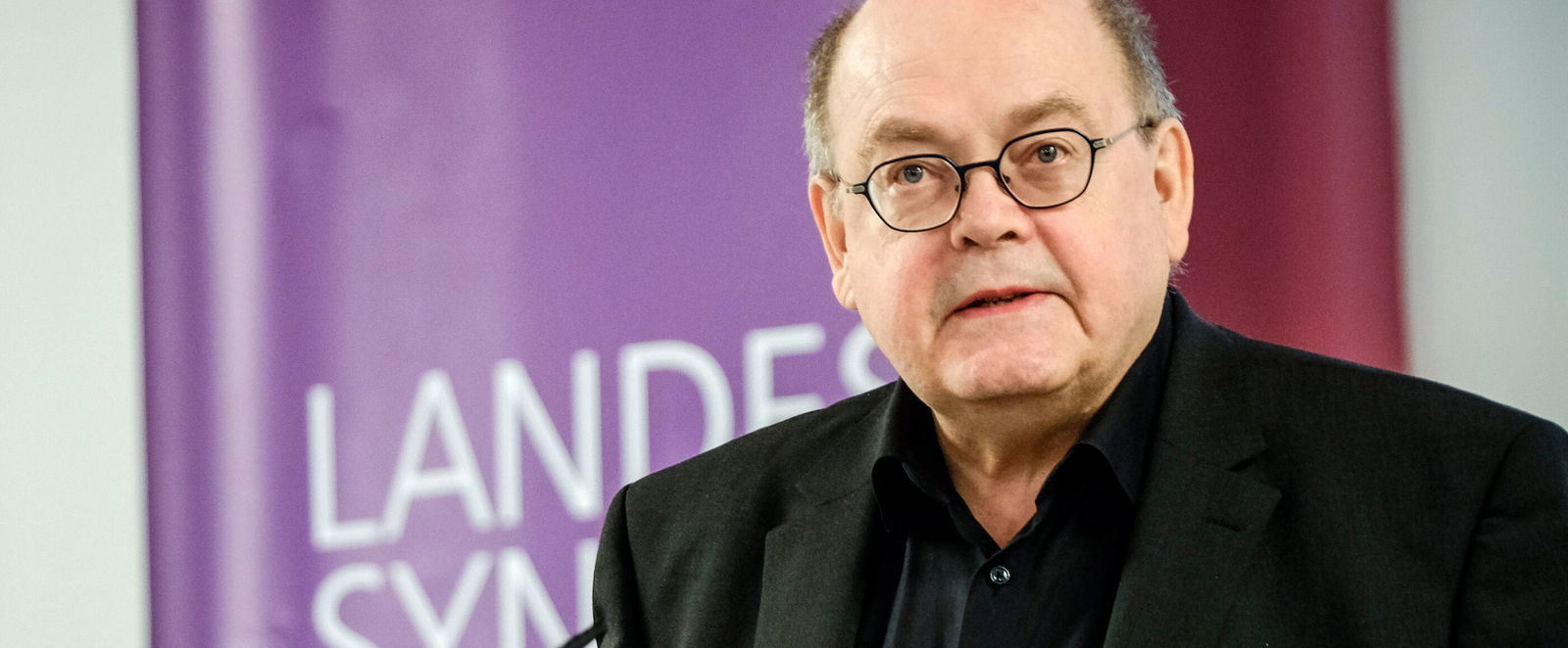 Eine männlich lesbare Person an einem Rednerpult