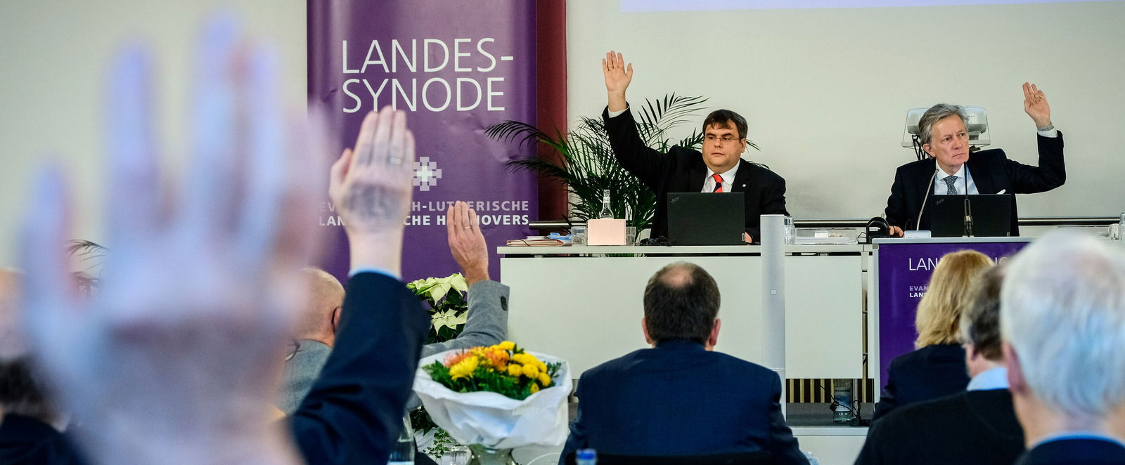 Personen haben die Hände erhoben und stimmen ab