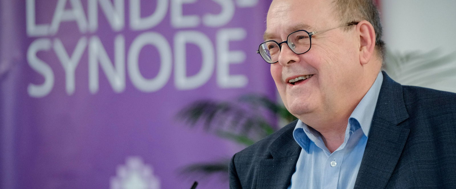 Eine männlich lesbare Person an einem Rednerpult