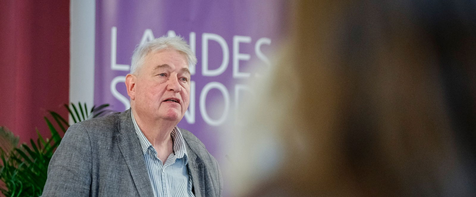 Eine männlich lesbare Person an einem Rednerpult