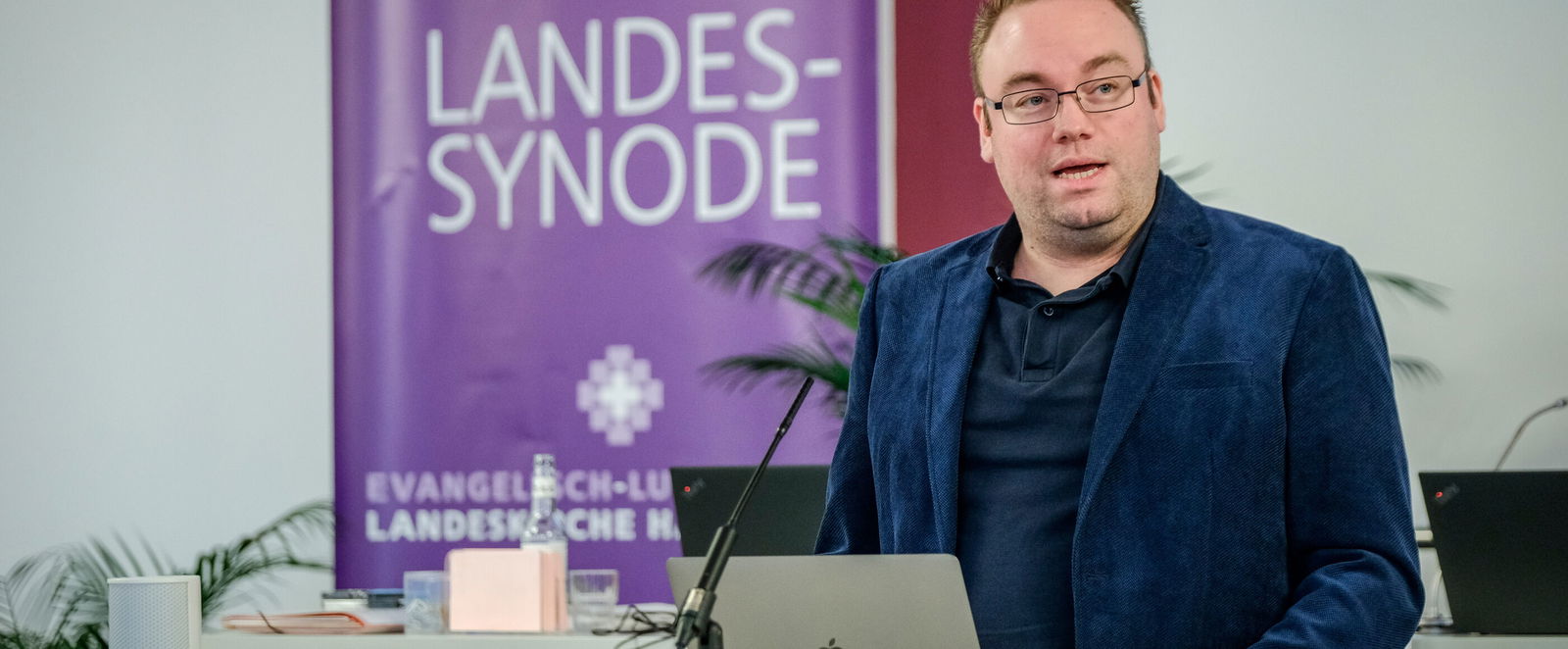 Eine männlich lesbare Person an einem Rednerpult