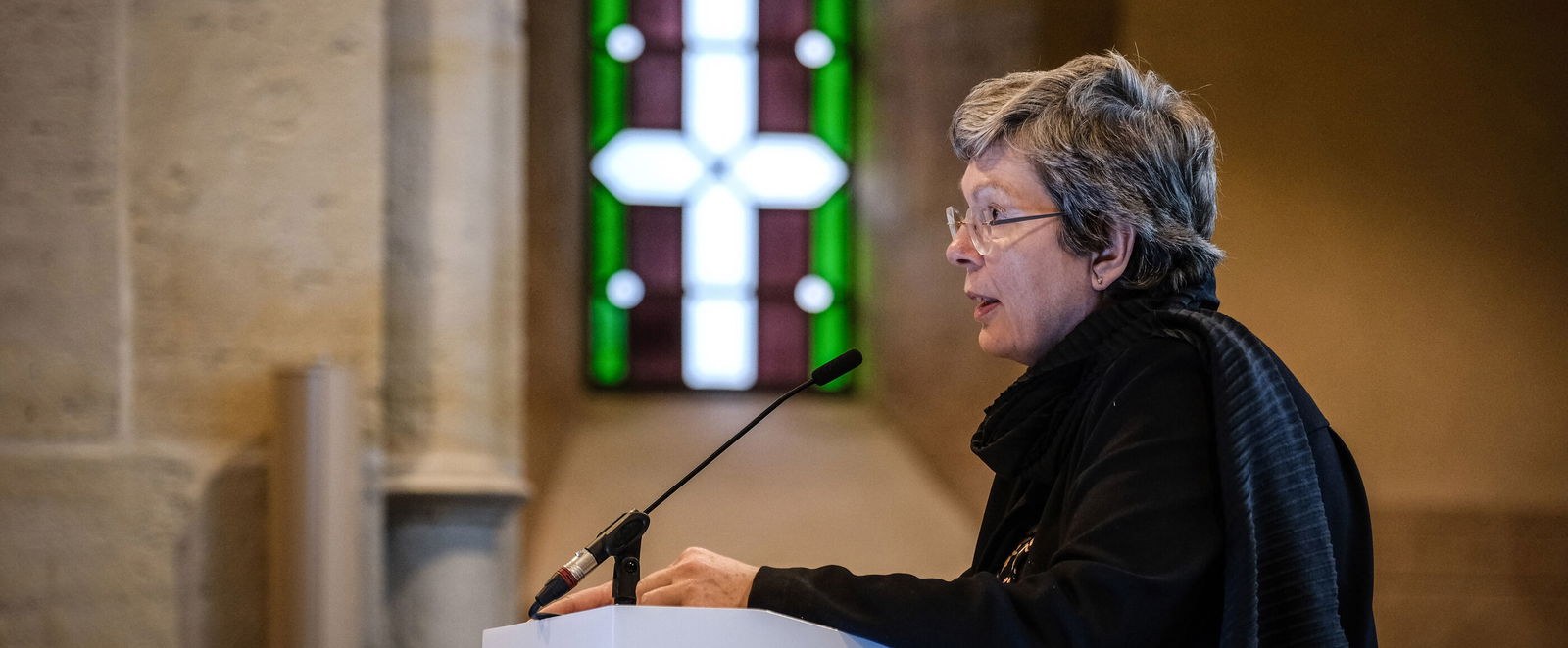 Eine weiblich lesbare Person steht an einem Podium und spricht.