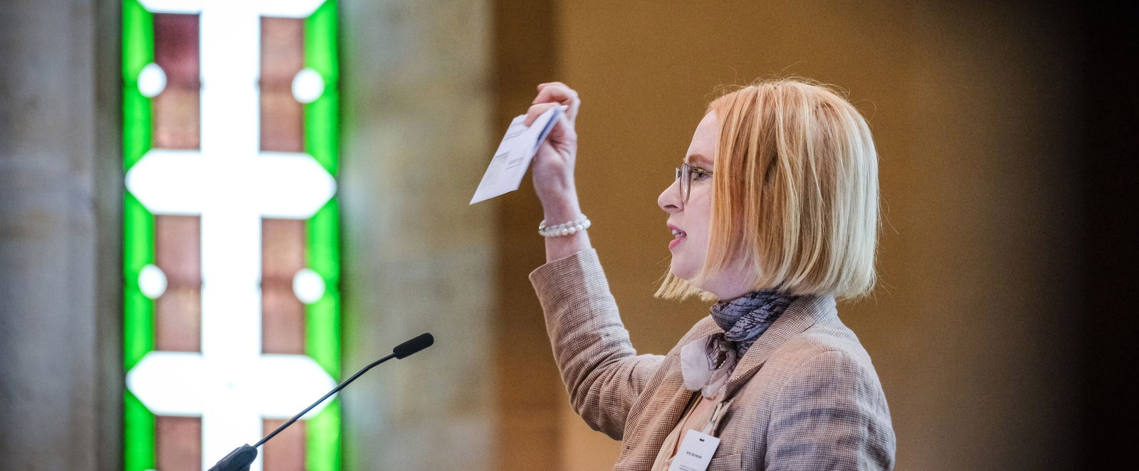 Eine weiblich lesbare Person steht an einem Podium und spricht.