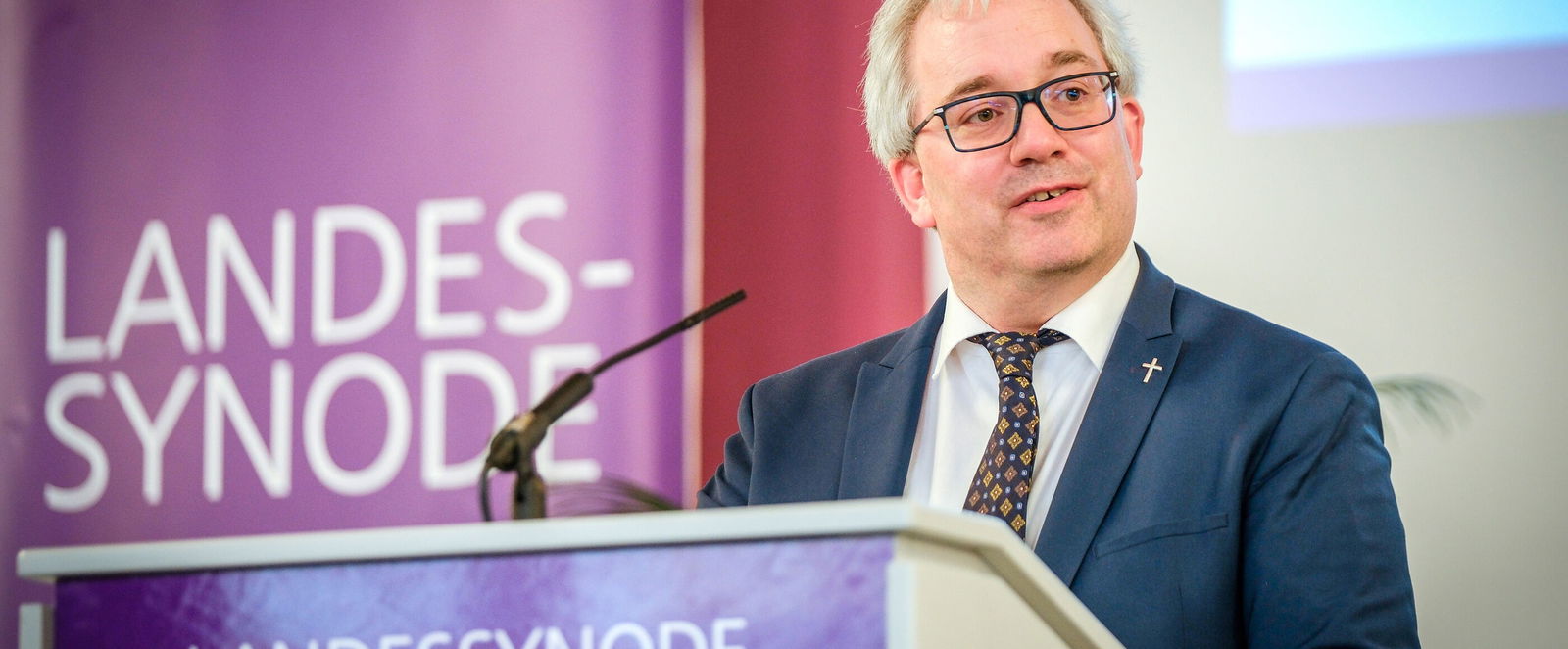 Eine männlich lesbare Person am Rednerpult