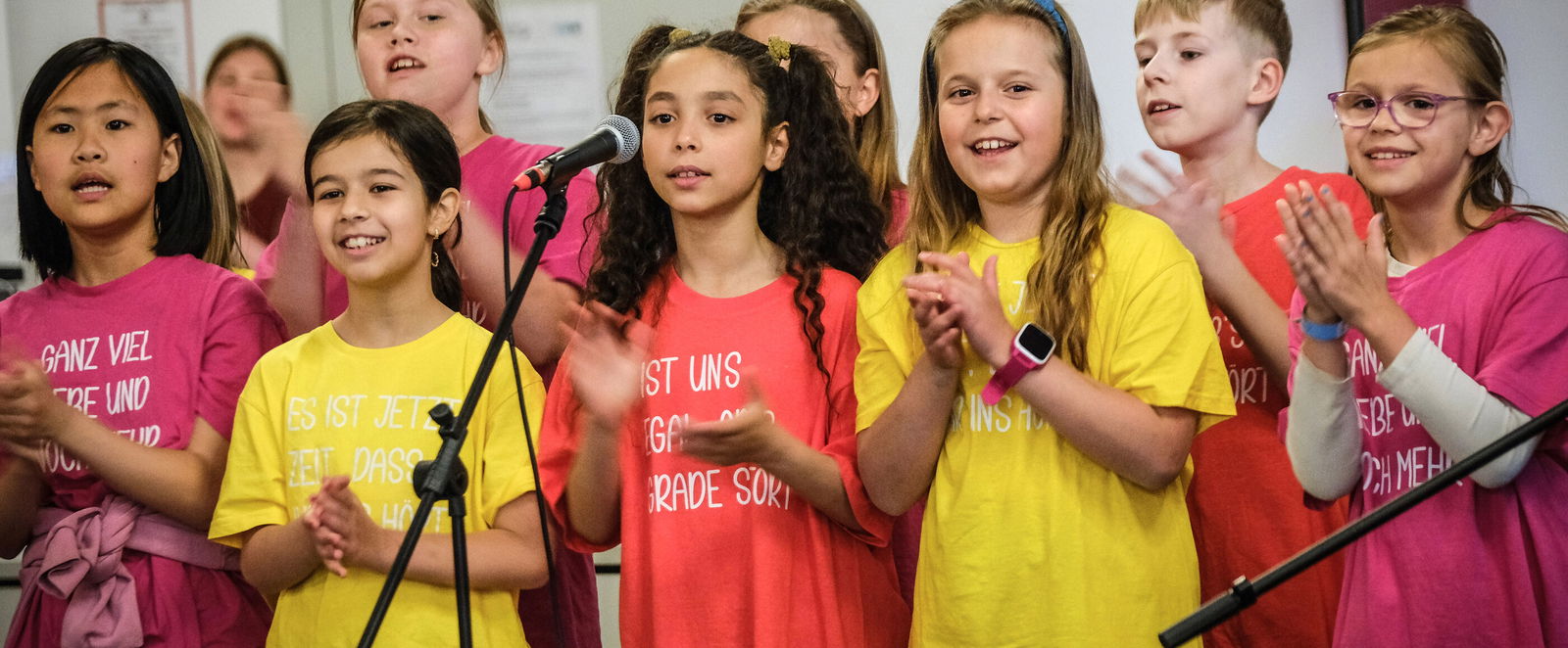 Mehrere Kinder, die singen und die Hände falten