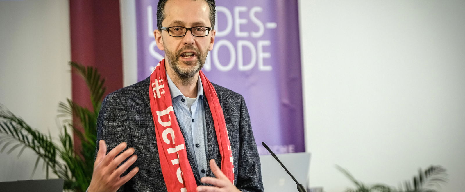 Eine männlich lesbare Person an einem Rednerpult