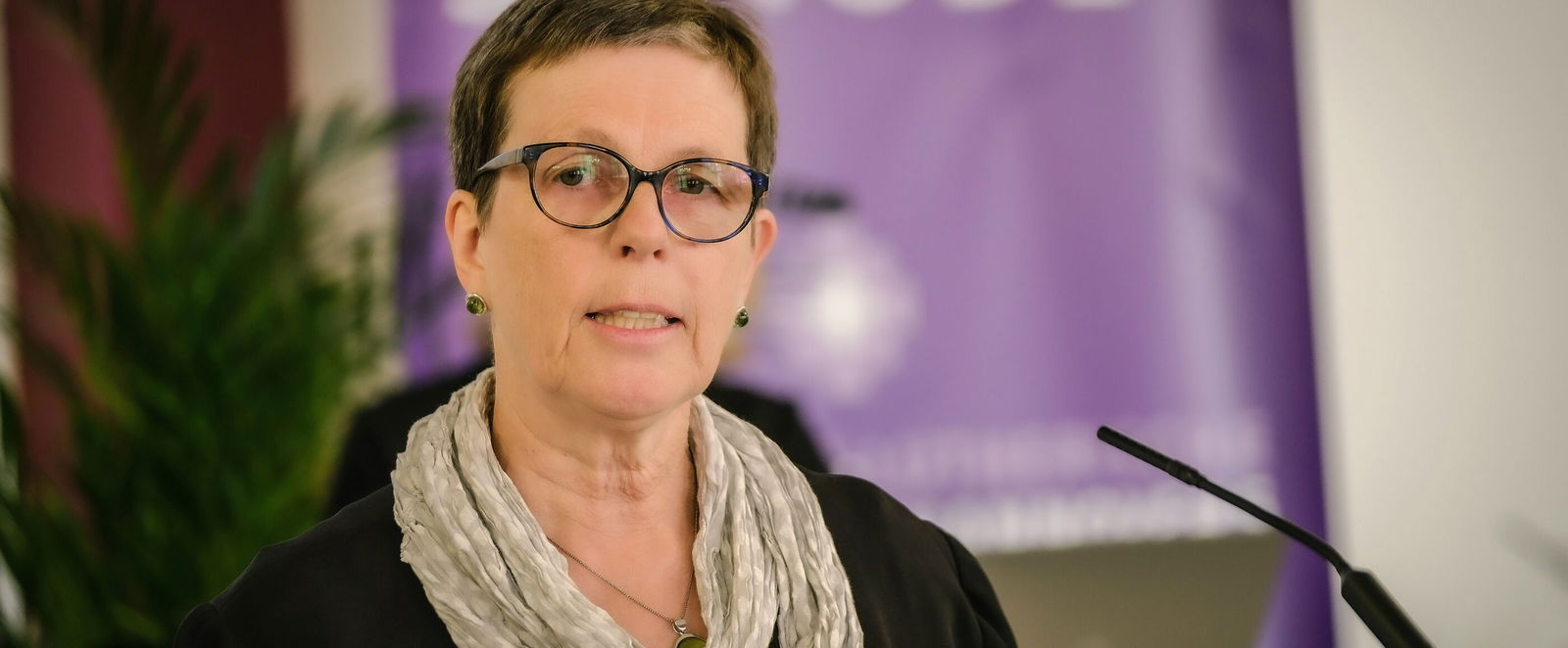 Eine weiblich zu lesende Person spricht in ein Mikrofon.