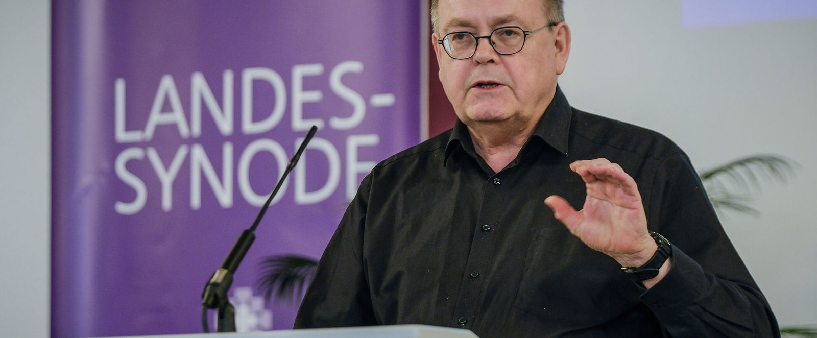 Eine männlich lesbare Person an einem Rednerpult