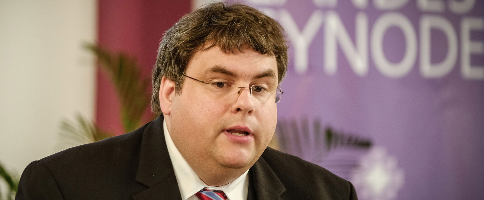 Eine männlich lesbare Person an einem Rednerpult