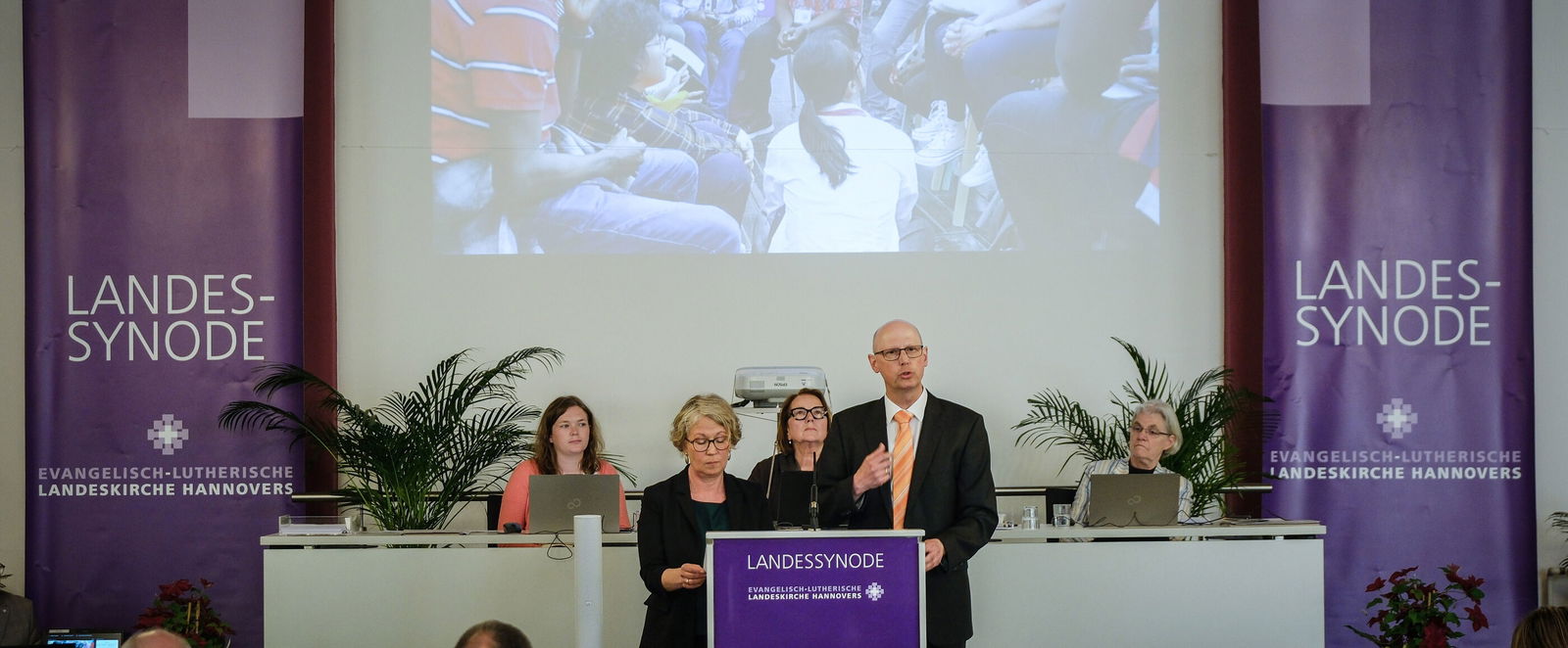 Mehrere Personen stehen vor einer Leinwand