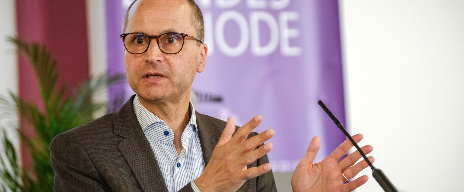 Eine männlich lesbare Person an einem Rednerpult