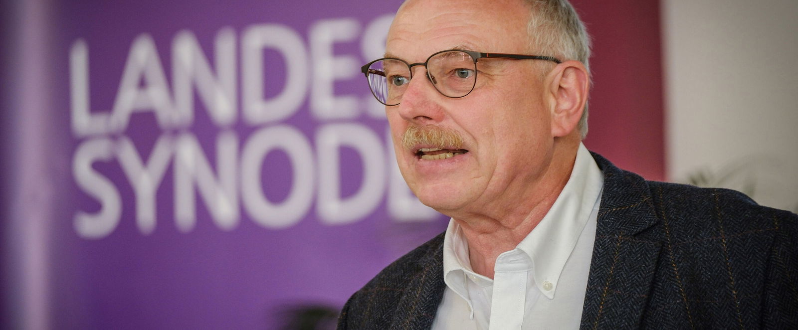 Eine männlich lesbare Person an einem Rednerpult