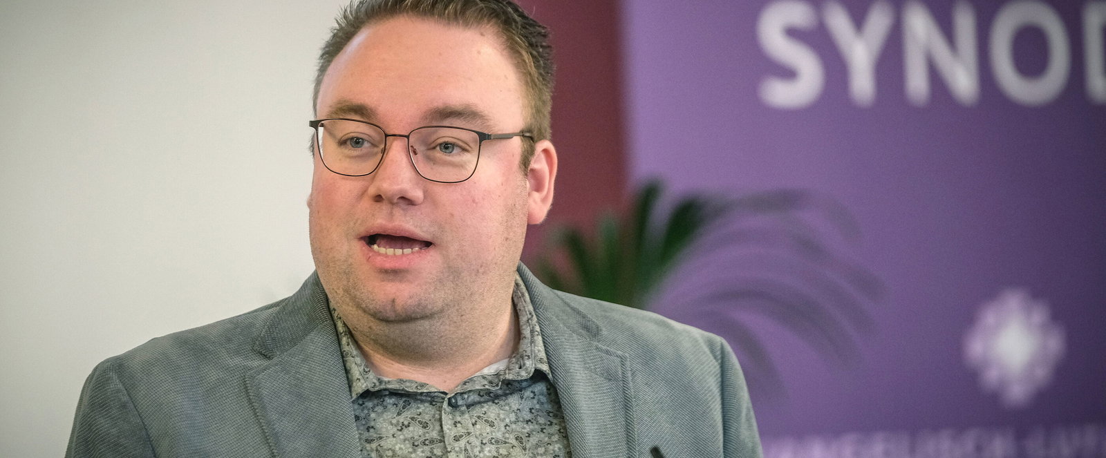 Eine männlich lesbare Person an einem Rednerpult