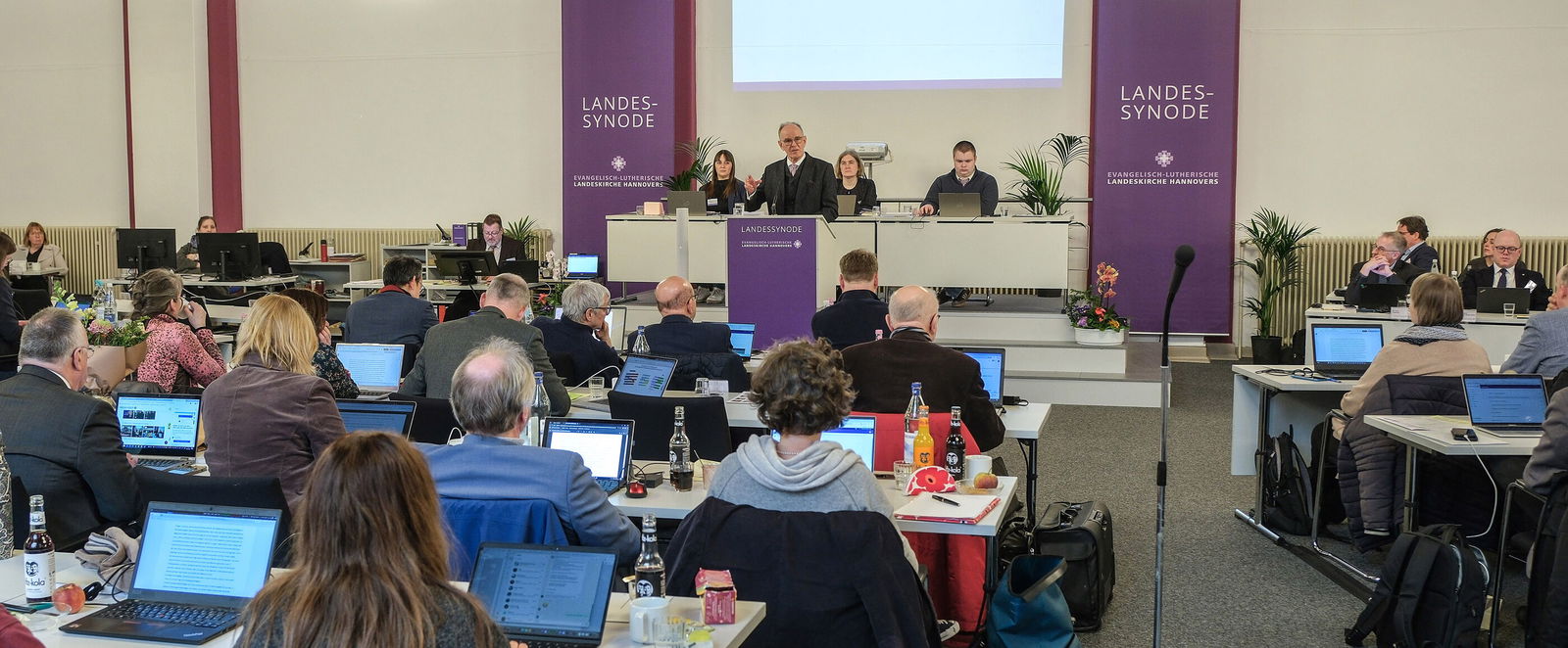 Viele Personen an Tischen in einem Sitzungssaal