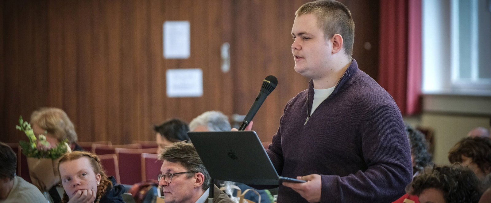 Eine männlich lesbare Person an einem Mikrofon