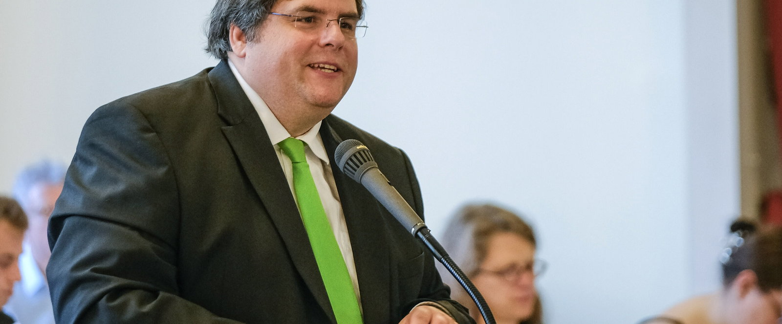 Eine männlich lesbare Person an einem Mikrofon