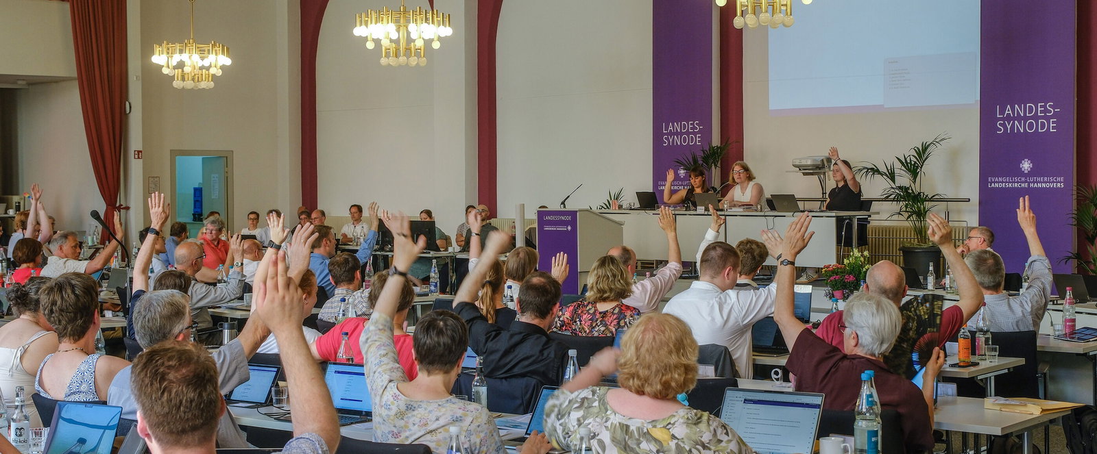 Viele Personen heben die Hand zur Abstimmung