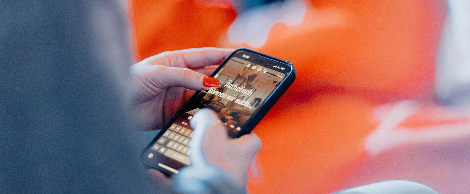 Blick an einem Arm vorbei auf ein Smartphone, auf dem steht: "Ästhetisch können wir auch"