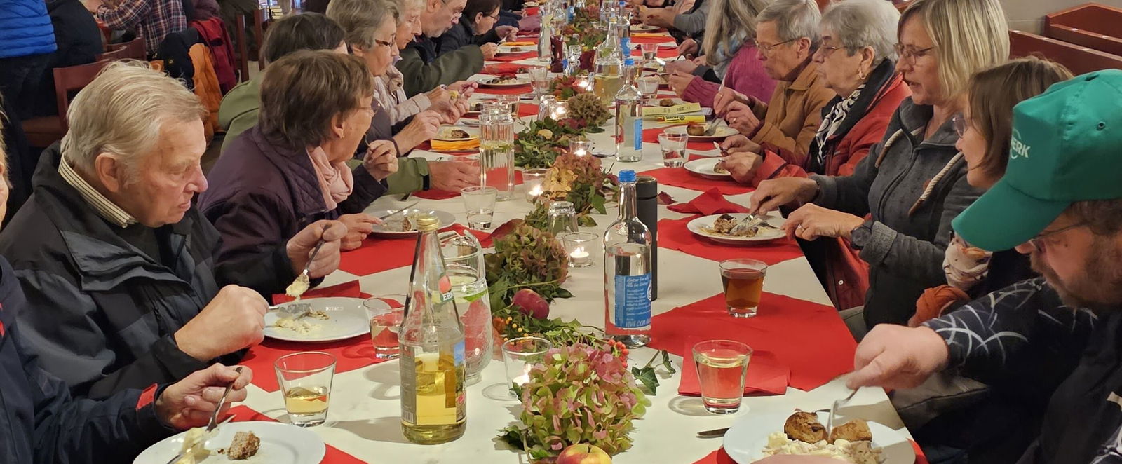 Viele Menschen sitzen an einer langen Tafel in einer Kirche.