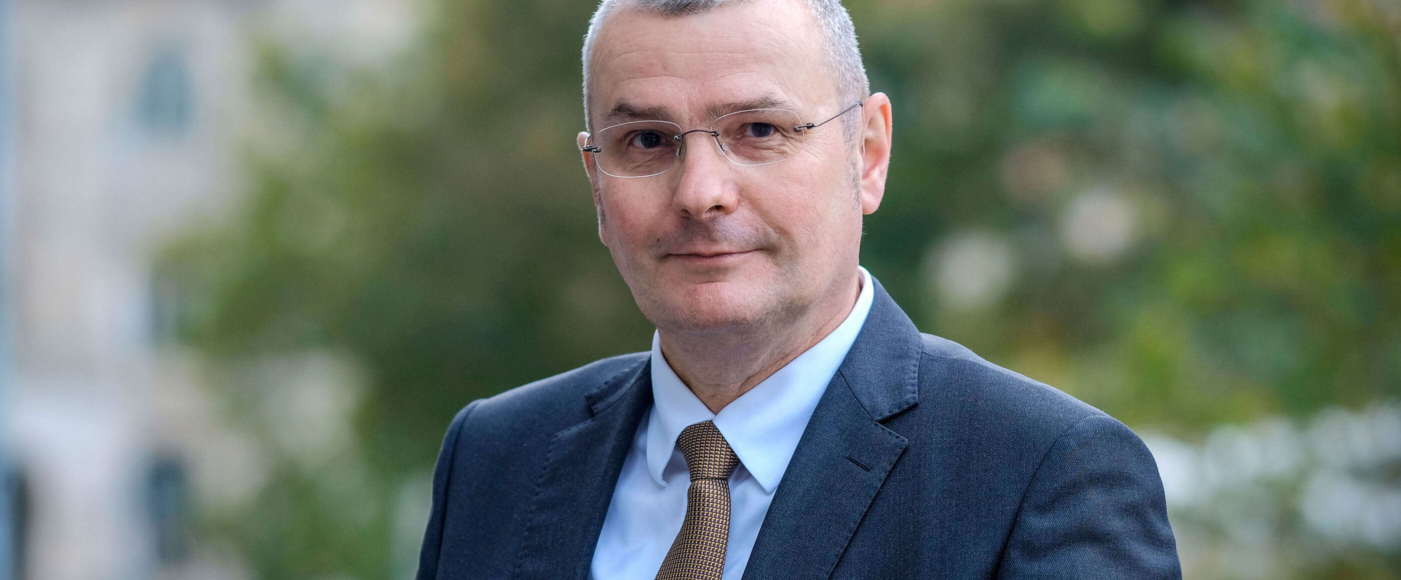 Ein Mann im Anzug, kurzen, grauen Haaren und Brille.