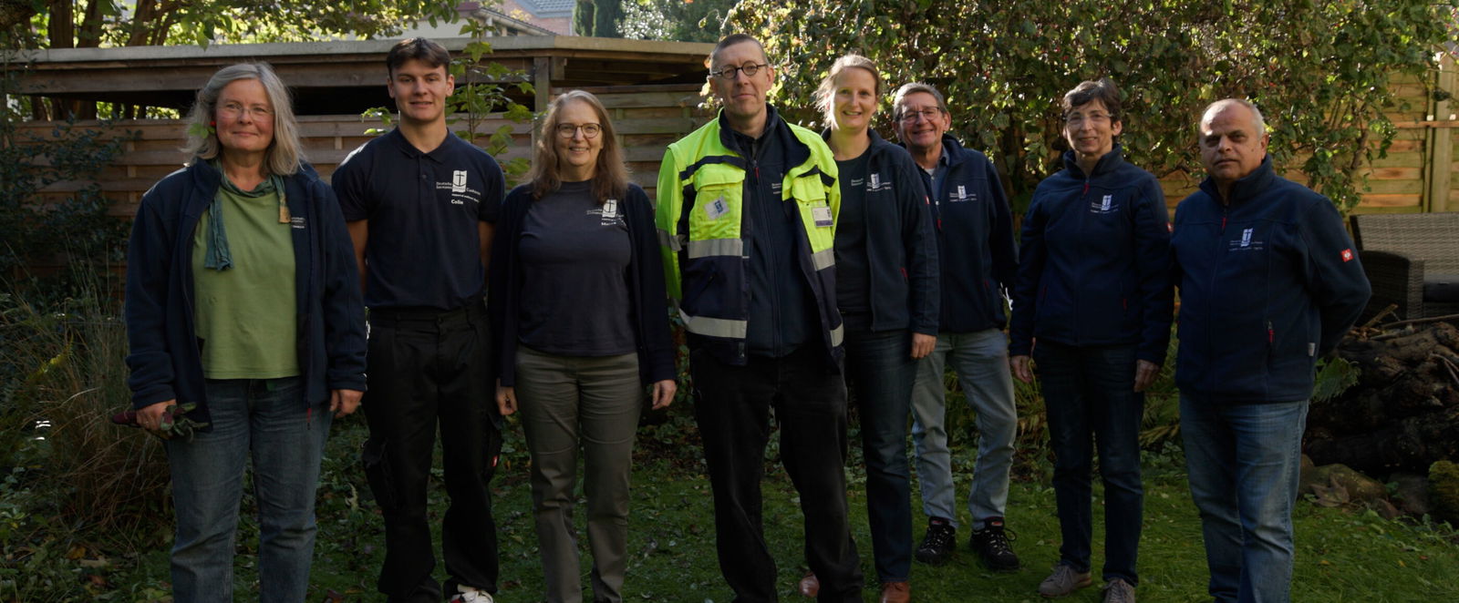 Mehrere Menschen stehen in einer Reihe im Grünen.