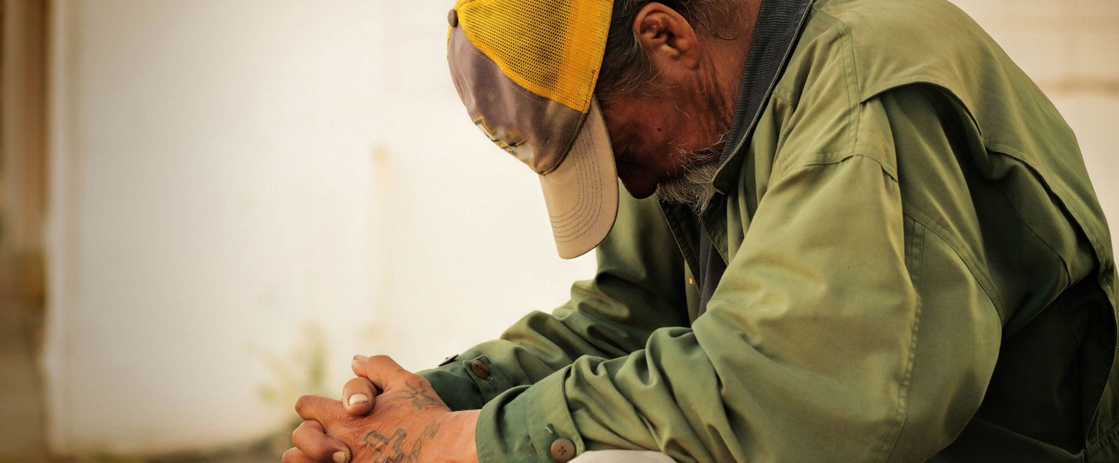 Ein Obdachloser sitzt in sich zusammengekauert.