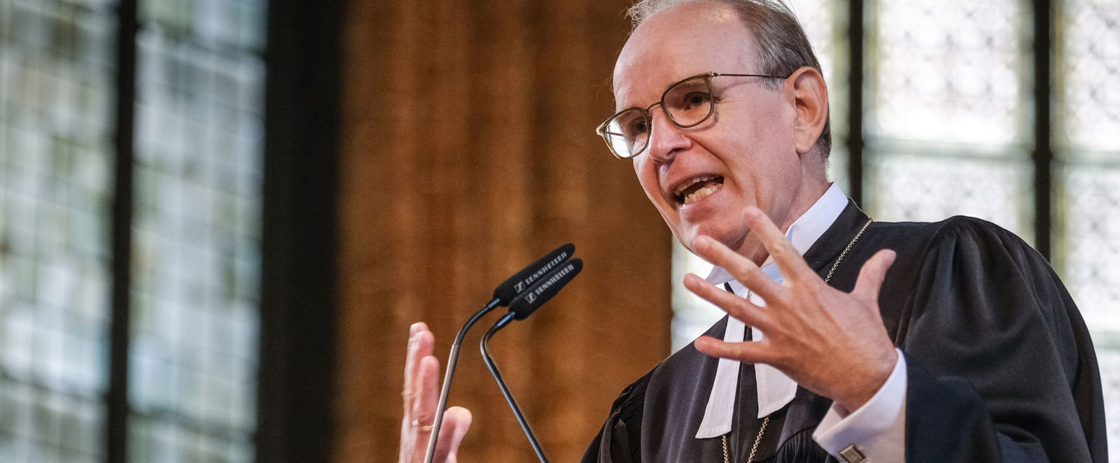 ein Mann in einem Bischofstalar steht in einer Kirche auf der Kanzel und Predigt