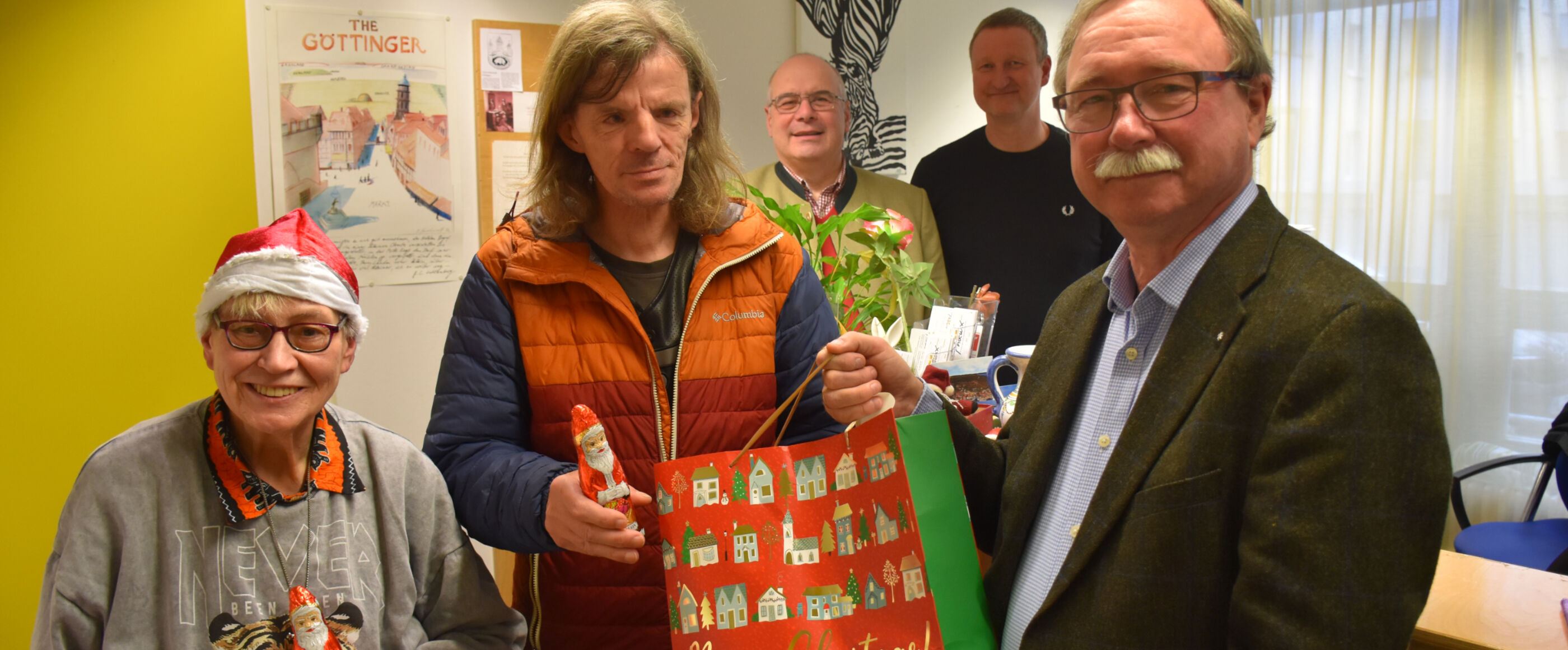eine Gruppe von Menschen mit Weihnachtstüten und Weihnachtsmützen
