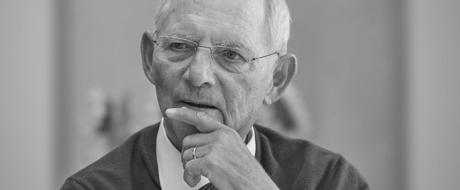 Ein älterer Mann hält nachdenklich die Hand an den Mund.